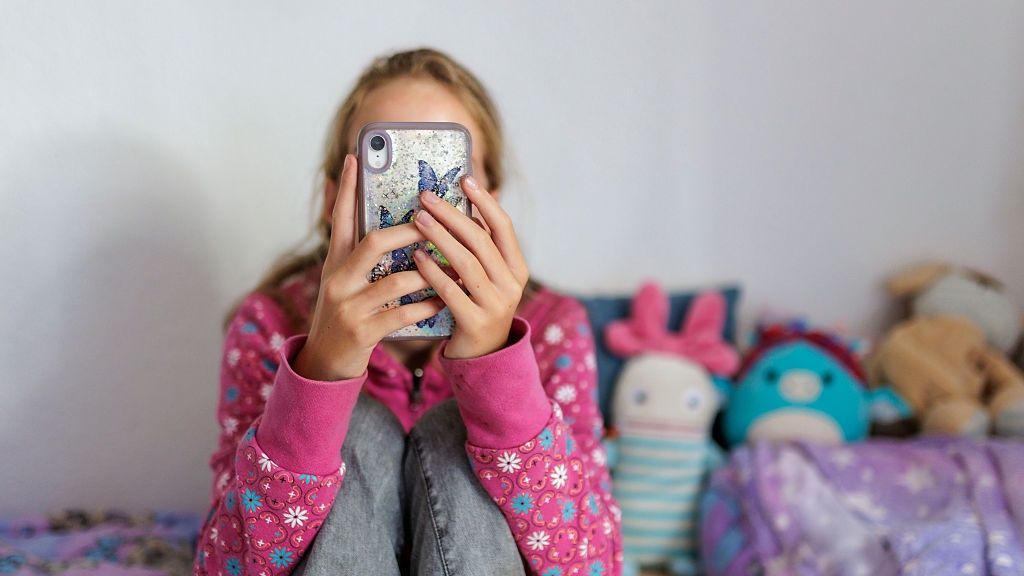 Dziewczynka korzystająca ze smartfona, zdjęcie poglądowe