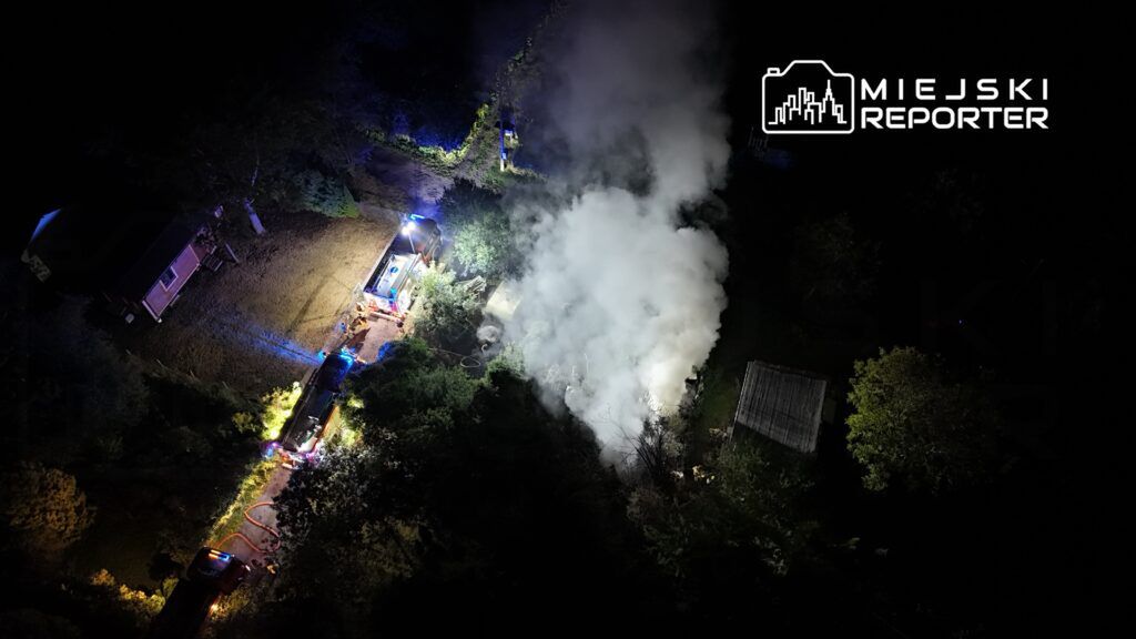 Strażacy gaszą pożar w lesie, otoczeni gęstym dymem, przy użyciu specjalistycznego sprzętu i wozów ratunkowych.