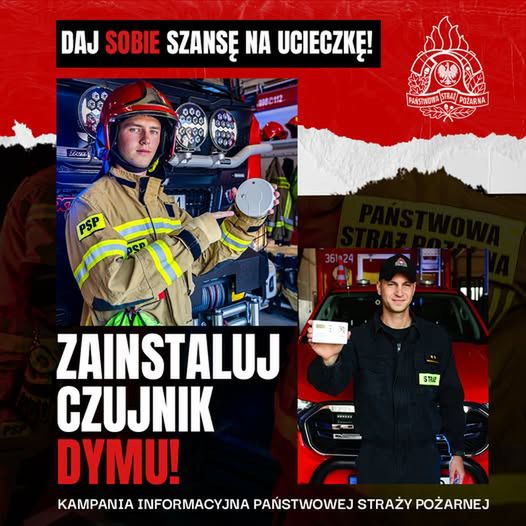 Strażak w mundurze trzyma czujnik dymu w jednostce strażackiej, obok niego drugi strażak z ulotką informacyjną.