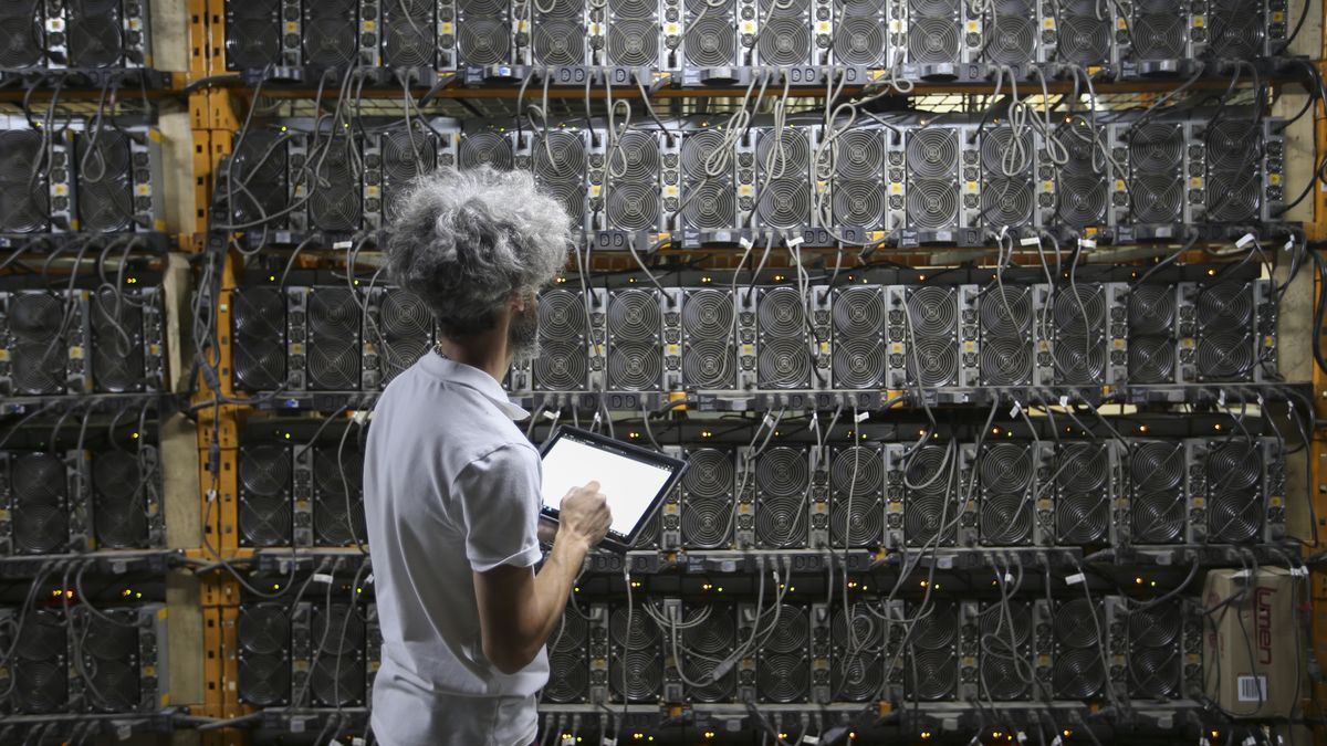 A worker inspects Bitcoin mining machines at a Canada Computational Unlimited Inc. computation center in Joliette, Quebec, Canada, on Friday, Sept. 10, 2021. CCU.ai, a Bitcoin mining center powered by hydroelectricity, has been conditionally approved for trading on the TSX Venture Exchange in Toronto under the stock symbol SATO. Photographer: Christinne Muschi/Bloomberg via Getty Images