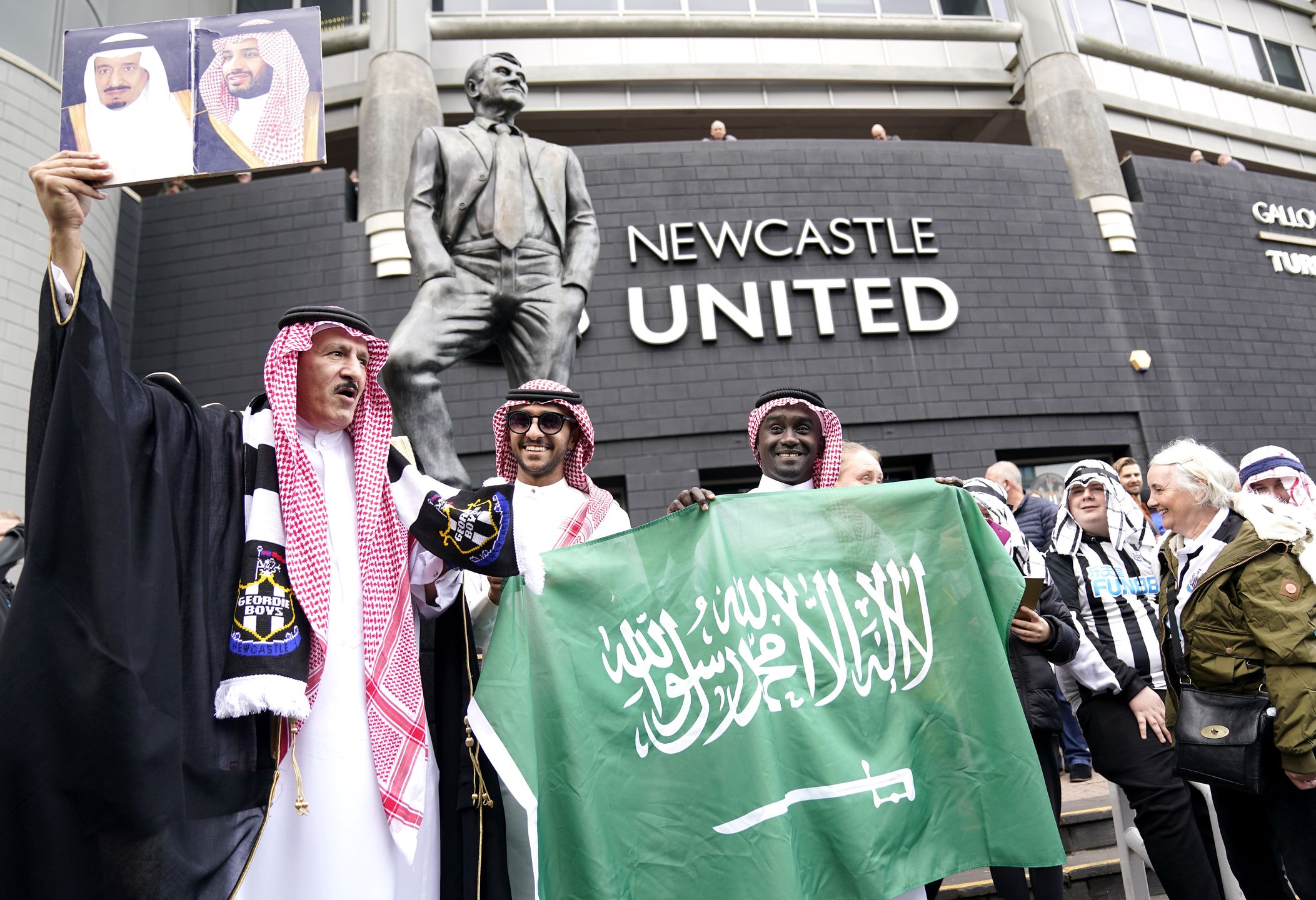 Newcastle United fans outside the stadium hold up a Saudi Arabia flag ahead of the Premier League match at St. James' Park, Newcastle. Picture date: Sunday October 17, 2021. (Photo by Owen Humphreys/PA Images via Getty Images)