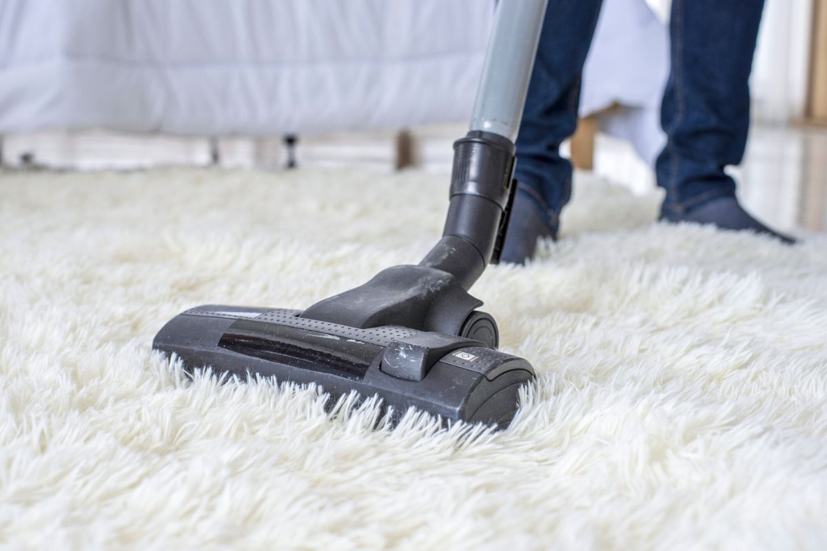 The man is vacuuming the carpet.