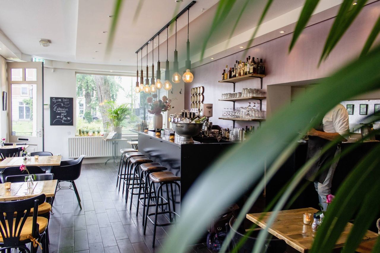 An interior shot of a cafe with chairs near the bar with wooden tables