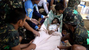 Filipińscy żołnierze i ochotnicy niosą 14-letniego chłopca, wydobytego spod gruzów