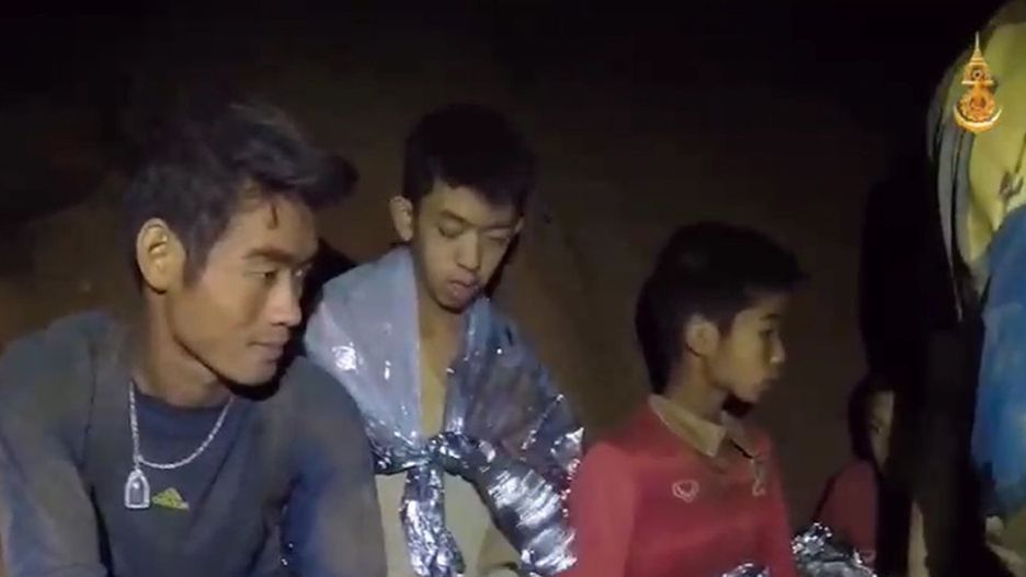 Odnalezione, ale jeszcze nie uratowane, dzieci i ich trener (na pierwszym planie) koczują na małej półce skalnej