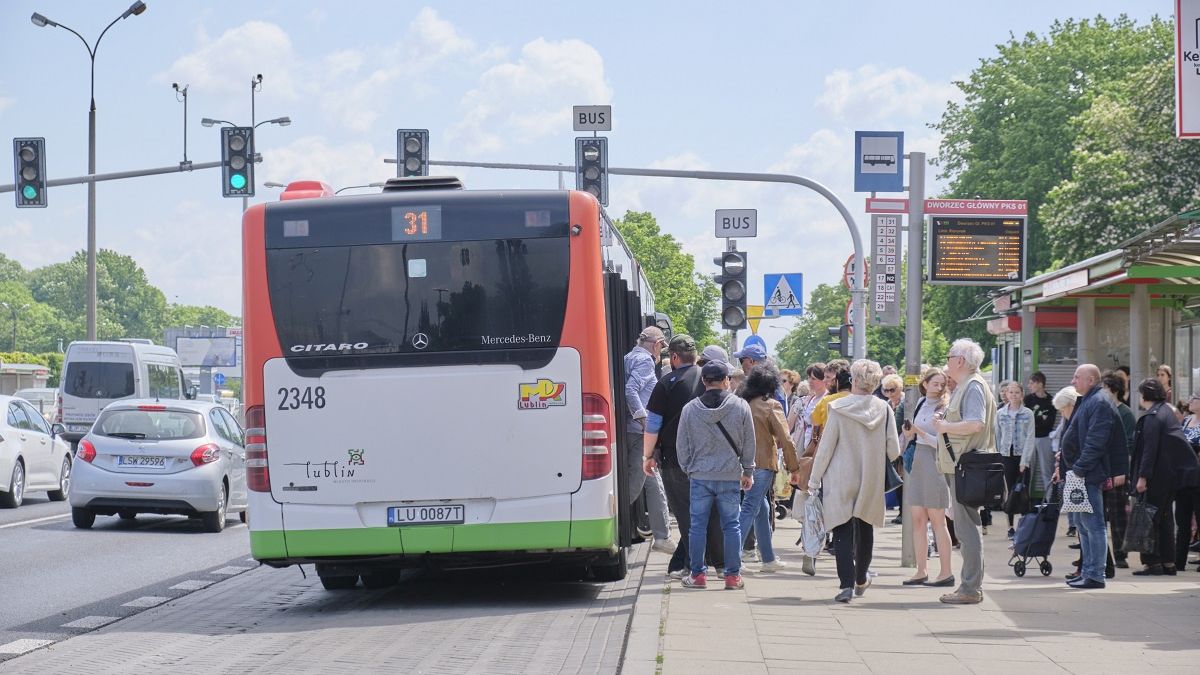 Pasażerowie wsiadający do autobusu na przystanku