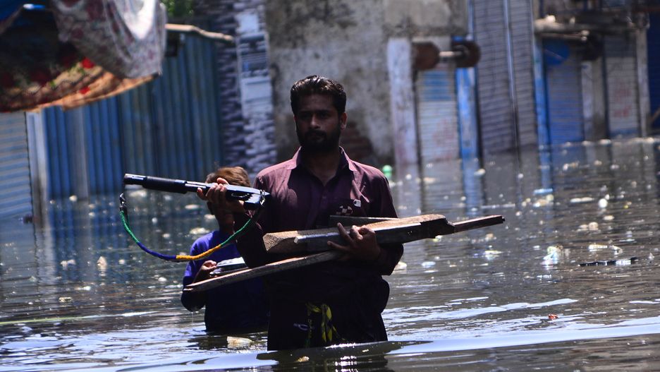 DADDU, PAKISTAN, SEPTEMBER, 07:   Pakistani flood victims carry their belongings as they wade through floodwater l   following flash flood in Daddu district southern Sindh province, Pakistan, on September 07, 2022. Record monsoon rains and melting glaciers in Pakistan's northern mountains have brought floods that have affected 33 million people and killed at least 1,314, including 458 children, Pakistan's National Disaster Management Agency said. (Photo by Farhan Khan/Anadolu Agency via Getty Images)