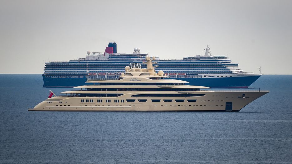 WEYMOUTH, ENGLAND - JUNE 08: Super yacht Dilbar, owned by Russian billionaire Alisher Usmanov, anchors alongside the cruise ship Queen Victoria in Weymouth bay on June 08, 2020 in Weymouth, United Kingdom. As the British government further relaxes Covid-19 lockdown measures in England, this week sees preparations being made to open non-essential stores and Transport for London handing out face masks to commuters. International travelers arriving in the UK will face a 14-day quarantine period. (Photo by Finnbarr Webster/Getty Images)