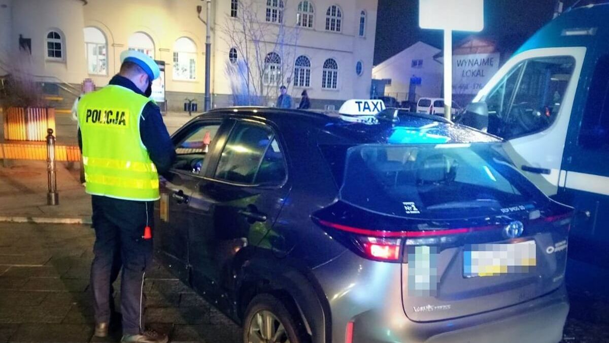Policjant kontrolujący kierowcę taksówki na aplikację