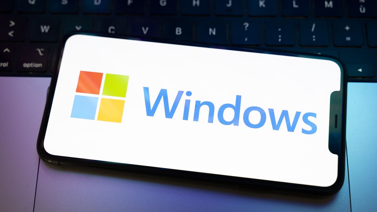The Windows logo appears on the screen of a smartphone placed on a computer keyboard illuminated by purple and blue light. Microsoft releases a major update to Windows 11 (25H2) and Windows 10 support ends permanently on October 14. In Creteil, France, on October 9, 2025. (Photo by Samuel Boivin/NurPhoto via Getty Images)