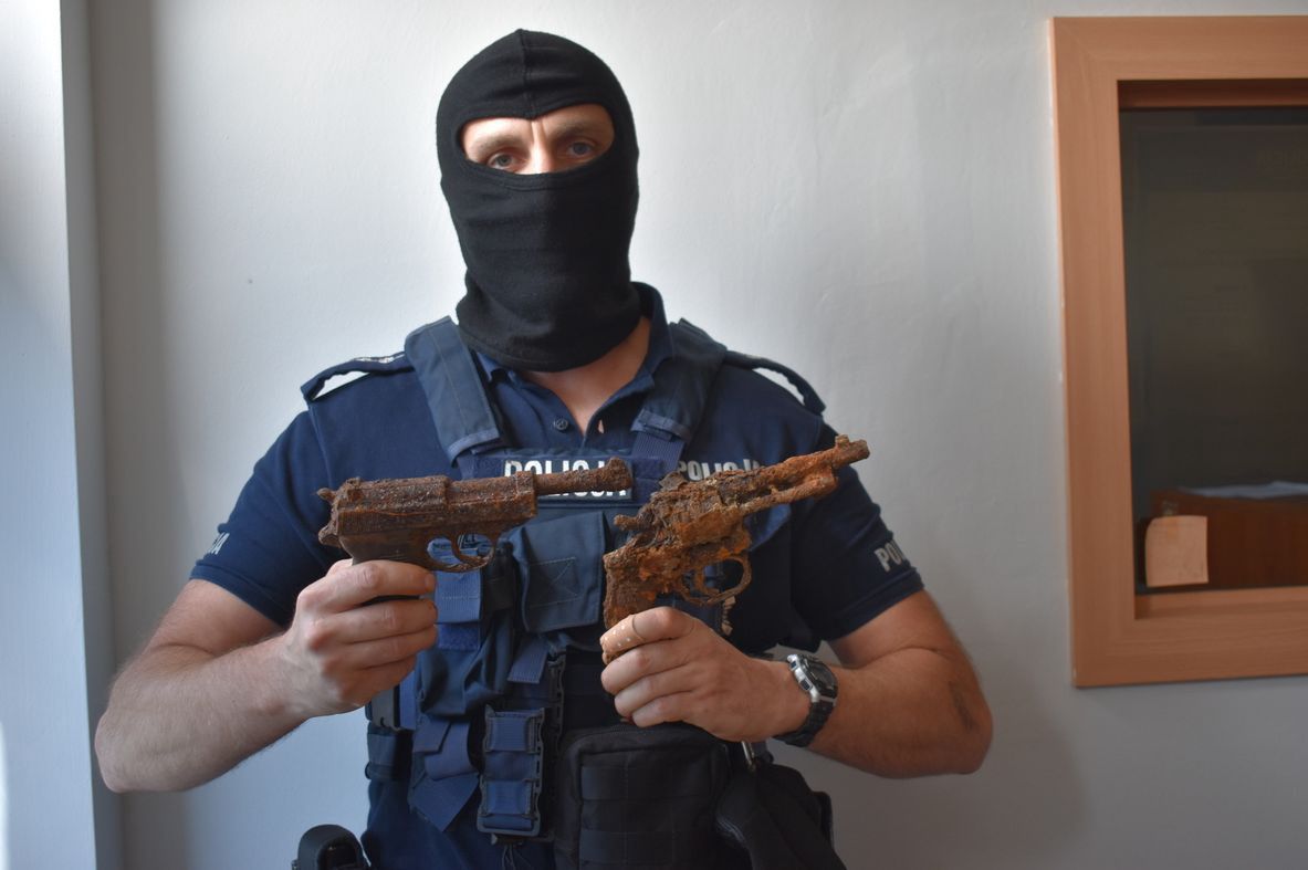 Funkcjonariusz policji prezentuje odnalezioną broń.