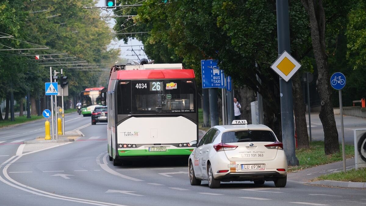 Autobus i taksówka jadące po buspasie