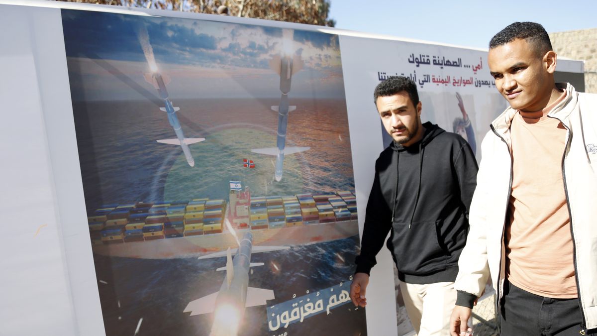 SANA'A, YEMEN - JANUARY 17: Yemeni men walk next to a billboard bearing the image of targeting a ship carrying an Israeli flag by missiles on January 17, 2024 in Sana'a, Yemen. The United States has re-designated Yemen's Houthi movement as a Global terrorist group, following months of the movement's attacks on ships considered by the Houthis owned or linked to Israel, in response to the Israeli war on the Gaza Strip. (Photo by Mohammed Hamoud/Getty Images)