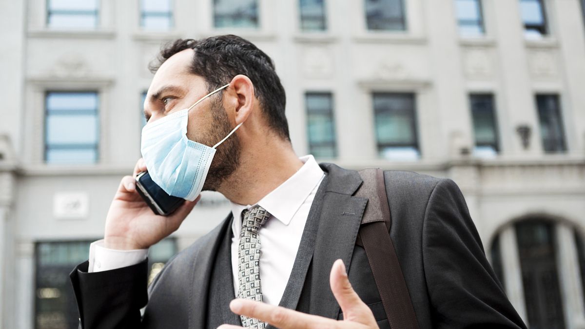 Business man on the street wearing a face mask to avoid COVID-19