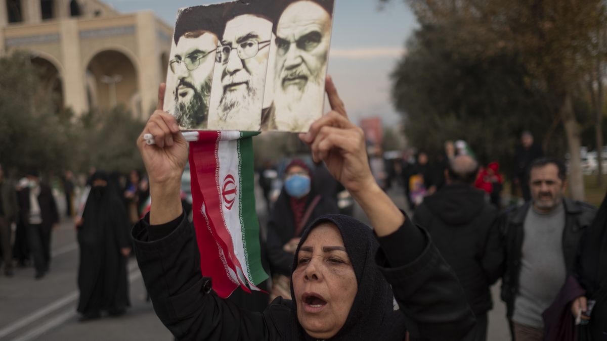 A veiled Iranian woman is shouting anti-U.S. and anti-Israel slogans as she carries portraits of the founder of the Islamic Republic Ayatollah Ruhollah Khomeini (R), Supreme Leader Ayatollah Ali Khamenei (C), and Secretary General of Lebanon's Hezbollah Hassan Nasrallah. She is participating in a rally to condemn  attacks in the city of Kerman, after Friday prayers in downtown Tehran, Iran, on January 5, 2024. More than 100 mourners, who were attending the Soleimani killing anniversary, have been killed in two  attacks in the city of Kerman. (Photo by Morteza Nikoubazl/NurPhoto via Getty Images)