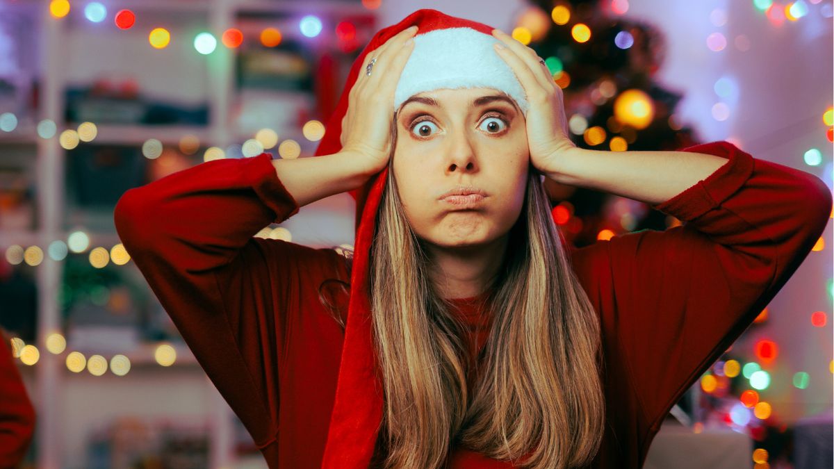Kobieta w czapce mikołaja łapie się za głowę