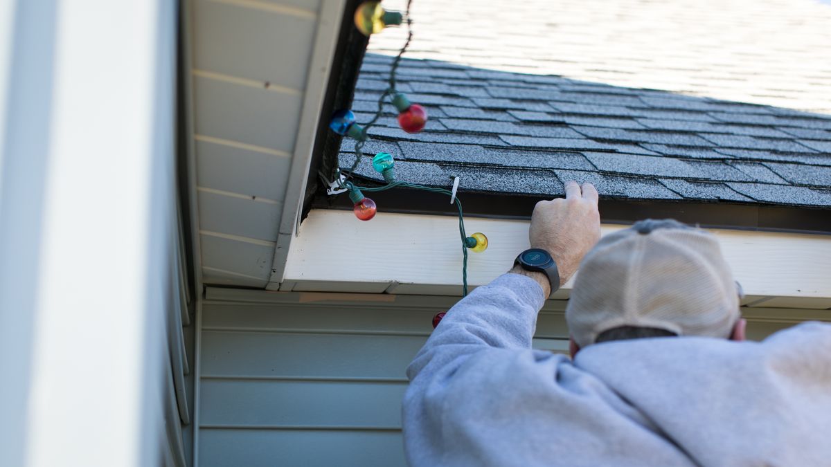 lights, xmas, christmas, hanging, man, string, bulbs, colorful, light, white, work, working, people, hand, hands, gutters, house, home, repair, person, caucasian, close up, sweatshirt, hat, decoration, holiday