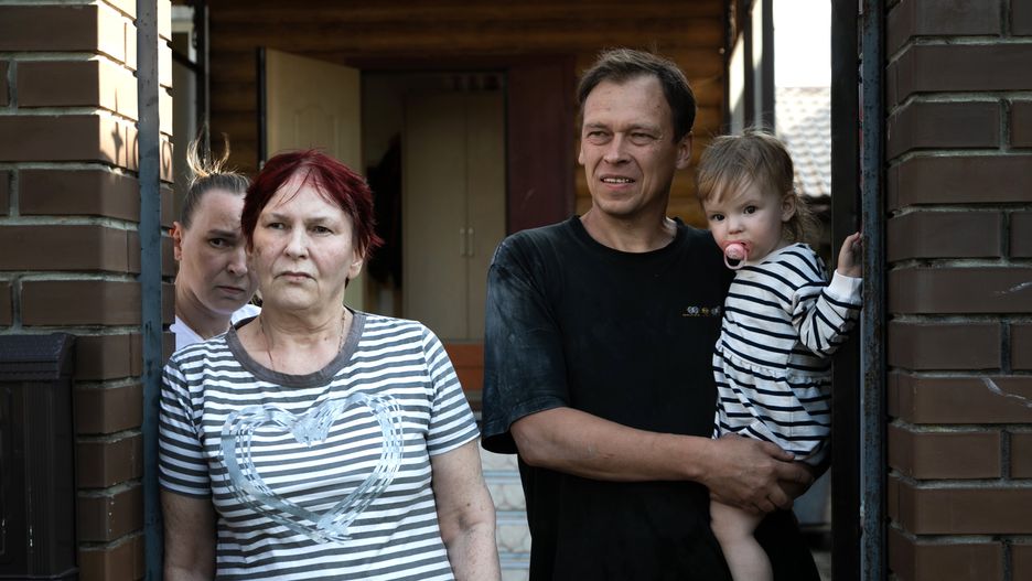 SUDZHA, RUSSIA - AUGUST 16, 2024 - Locals with a baby stand at the gate, Sudzha, Kursk Oblast, Russia. (Photo credit should read KIRILL CHUBOTIN / Ukrinform/Future Publishing via Getty Images)