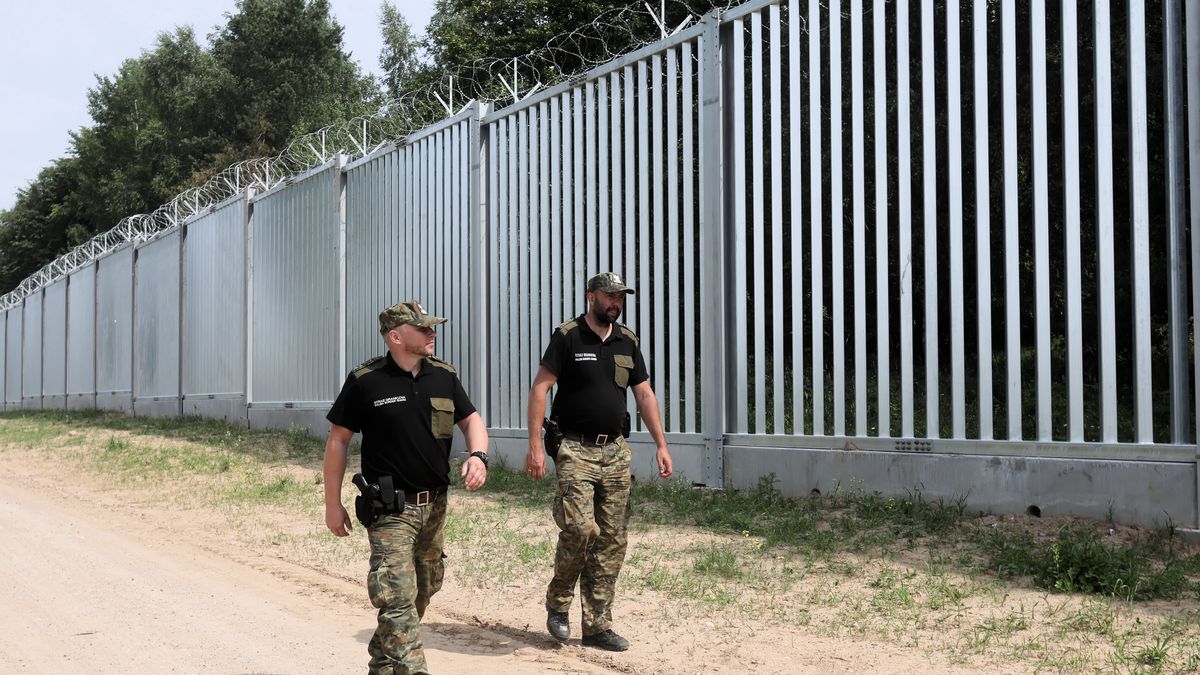 Na zdjęciu wojskowi przechadzający się obok muru na granicy