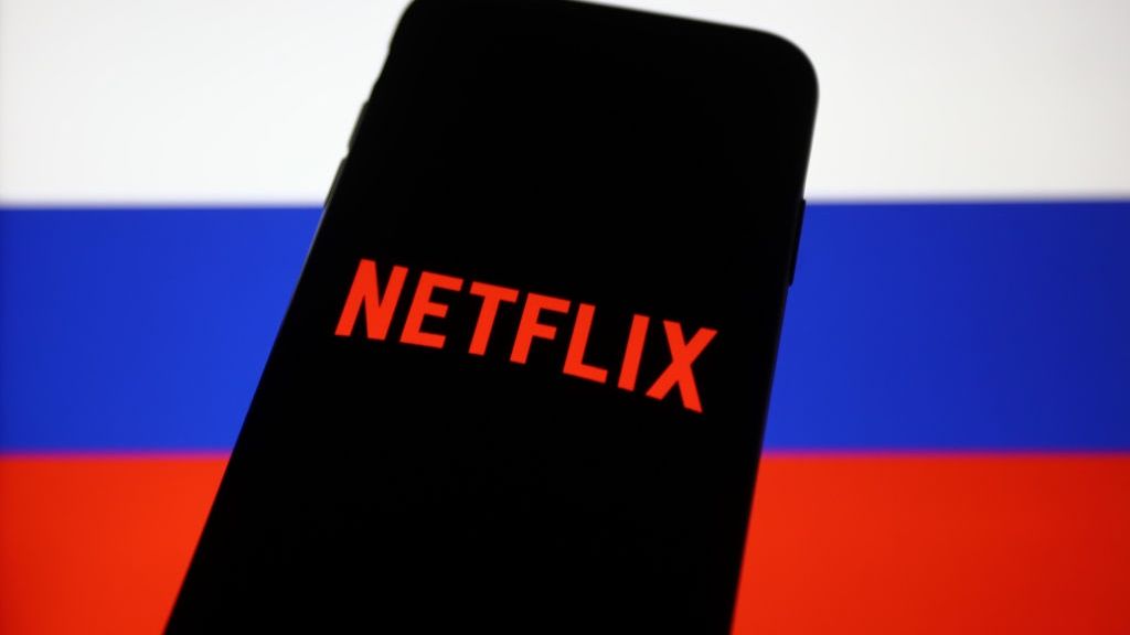 Logo Netfliksa w telefonie na tle rosyjskiej flagi