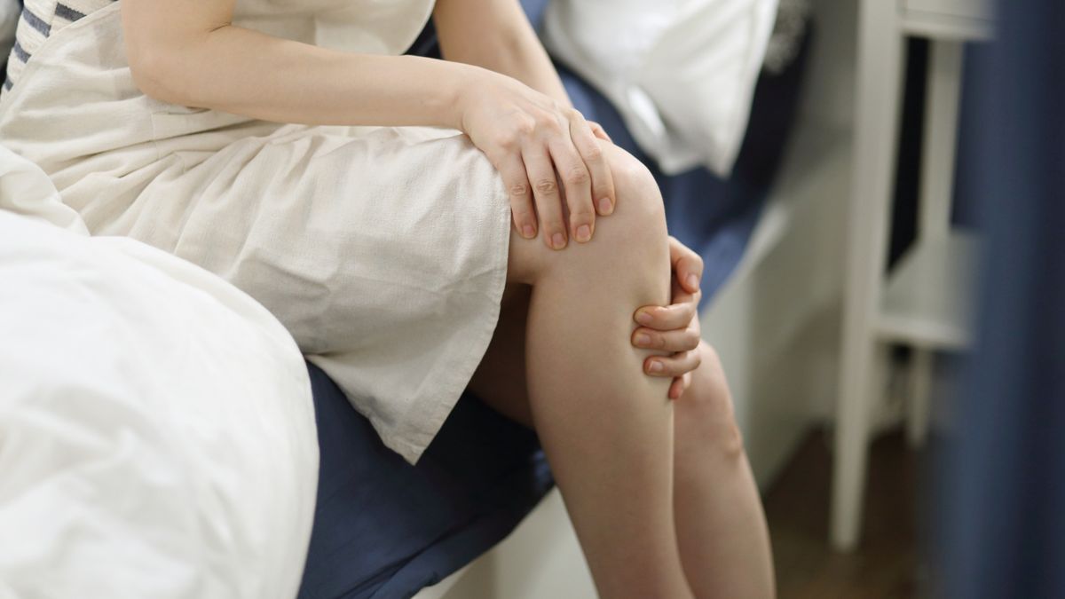 Woman with knee pain in bedroomRUNSTUDIO