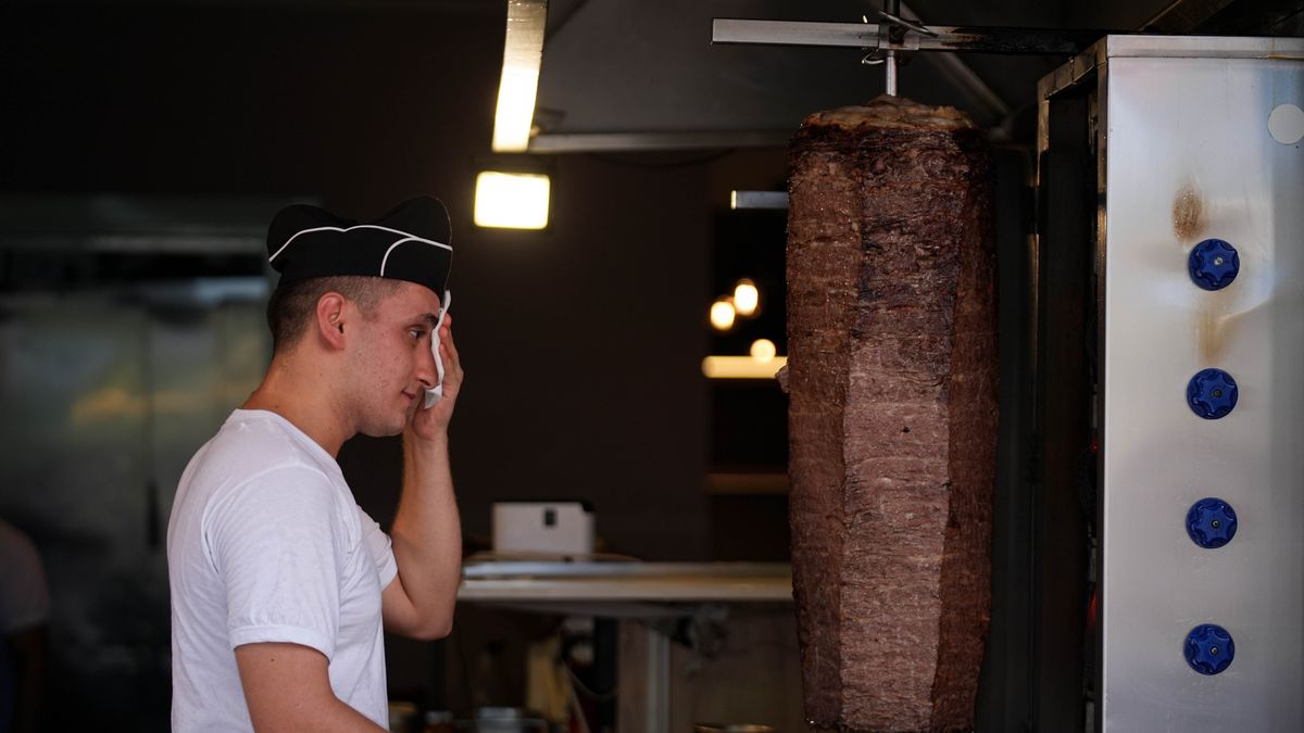 IZMIR, TURKIYE - AUGUST 10: The chef wipes sweat from his forehead while preparing doner kebab, as temperatures soar above 40 degrees in the Konak district of Izmir, Turkiye, on August 10, 2025. (Photo by Berkan Cetin/Anadolu via Getty Images)