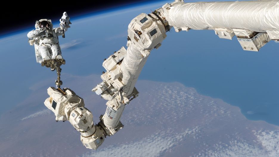 Astronauta przymocowany do końca ramienia Canadarm2