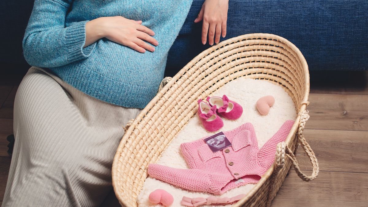 Kobieta w ciąży z ciuchami dziecka