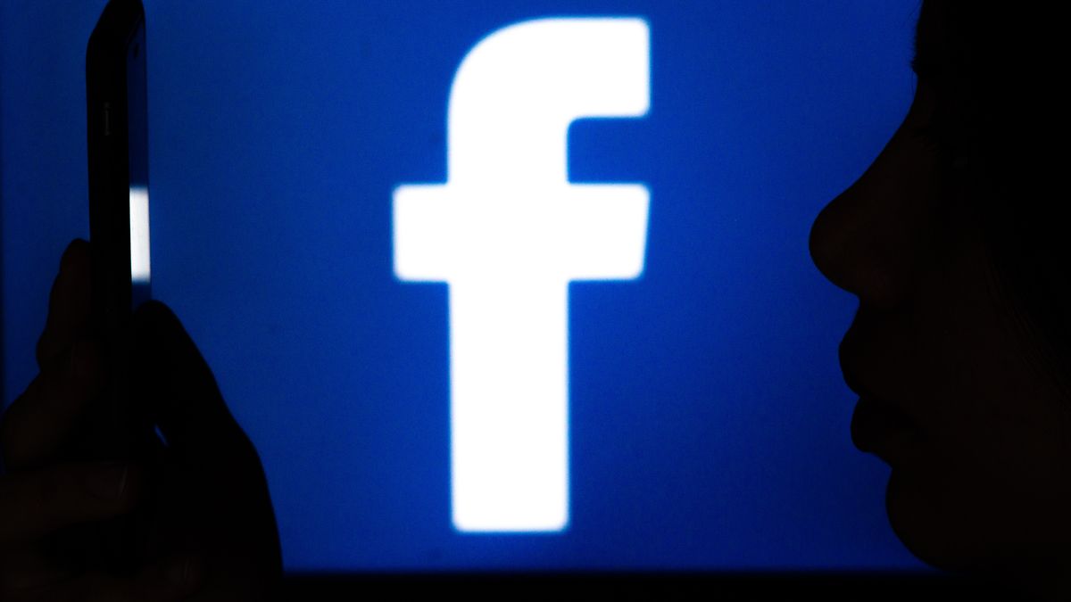 A Facebook logo background behind a woman using her smartphone is seen on February 20, 2023 in L'Aquila, Italy. Meta CEO Mark Zuckerberg announced the launch of a paid subscription starting at $11.99 per month for users to authenticate their profiles on Meta platforms (Facebook, Instagram). (Photo by Lorenzo Di Cola/NurPhoto via Getty Images)