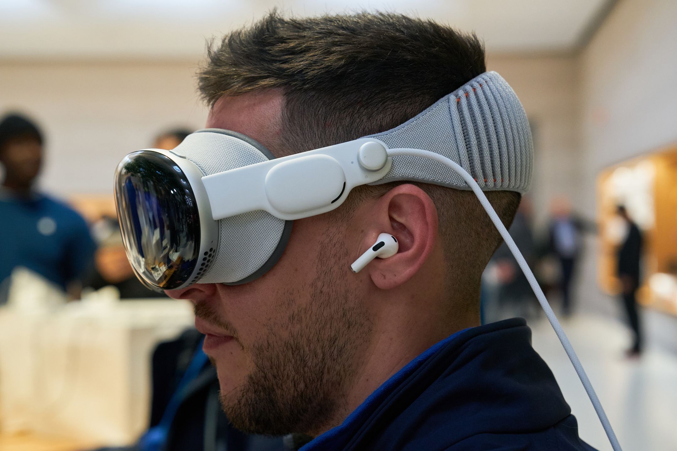 An employee of Rosellimac, an authorized reseller of Apple products, tries the Apple Vision Pro mixed reality (XR) headset while wearing AirPods at the company's Fifth Avenue store in New York, US, on Friday, Feb. 2, 2024. Apple Inc.'s first major new product in nine years arrives on Friday as the Vision Pro, a $3,499 mixed-reality headset, goes on sale in the US. Photographer: Bing Guan/Bloomberg via Getty Images