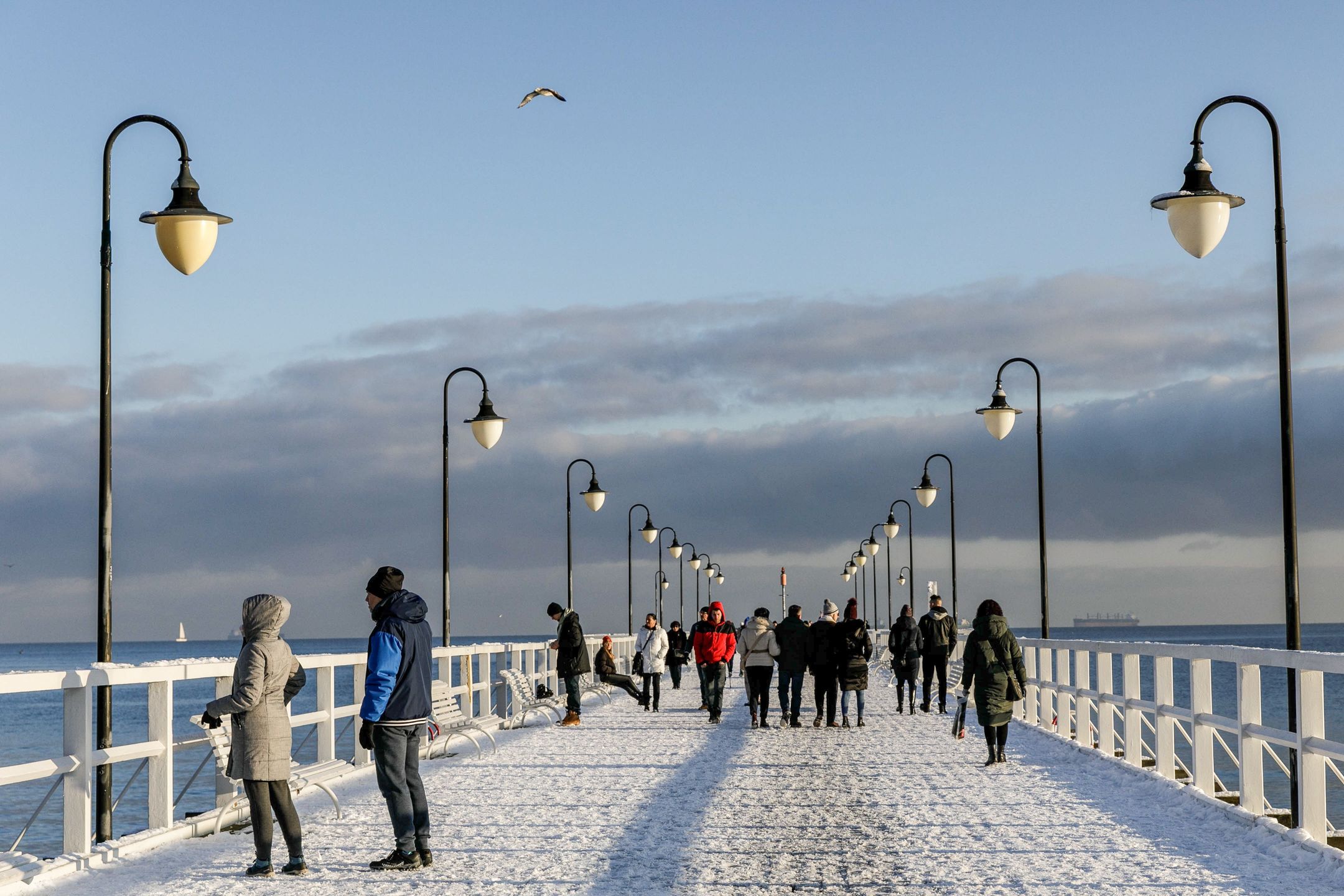GDYNIA, POLAND - 2022/12/10: People walk along the Gdynia Orlowo pier covered with snow. (Photo by Volha Shukaila/SOPA Images/LightRocket via Getty Images)