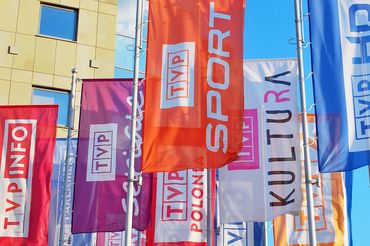 Flagi z logotypami kanałów obok głównej siedziby TVP
