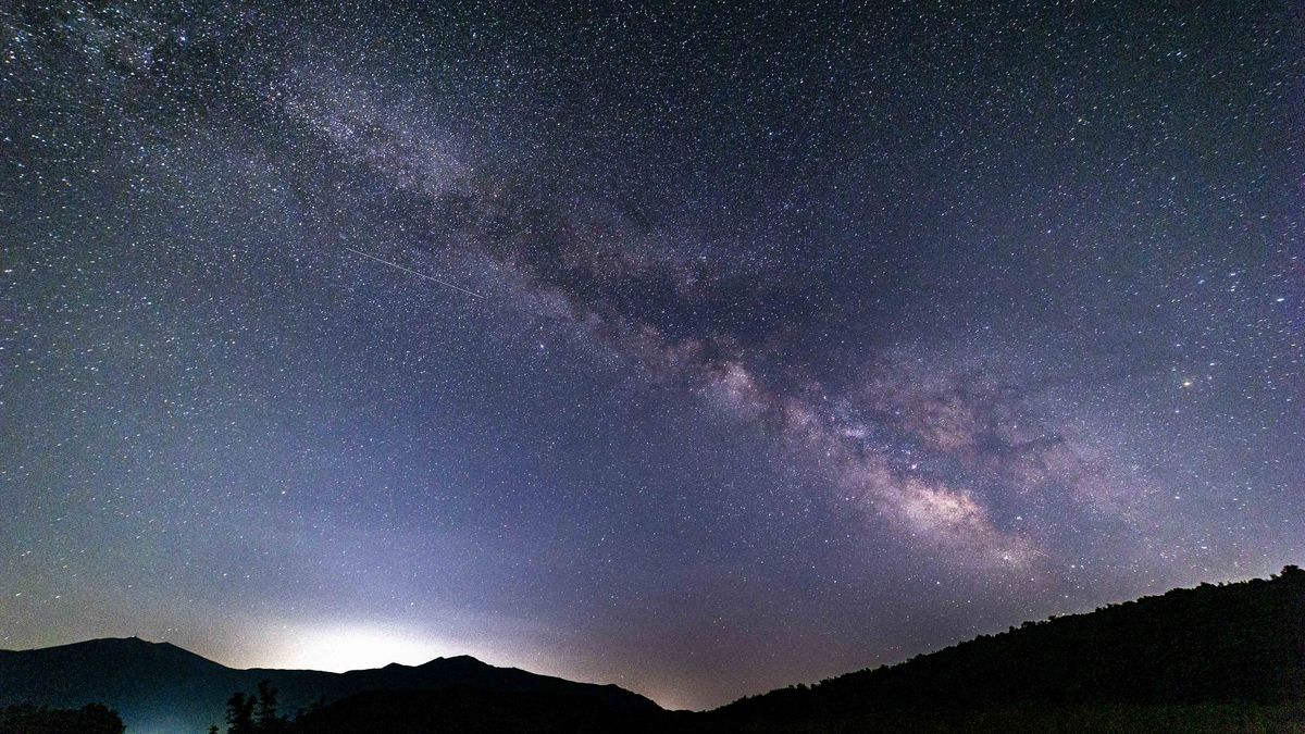 Milky Way captured with long exposure photography technique. Milkyway is the visible part of our galaxy seen during the dark night from the mountain area near Xanthi city in Northern Greece. Night landscape over the mountain with colourful Milky Way sky dome, the cloudless sky at mountains with the starry sky with hills at summer with the beautiful Universe and Space background. The Milky Way is a barred spiral galaxy the galaxy that includes the Solar System, with the name describing the galaxy appearance from Earth, a hazy band of light seen in the night sky formed from stars. The lines appearing are aircraft passing, satellite and meteorites while the lower light pollution comes from the city lights. Xanthi, Thrace, Greece on July 2024 (Photo by Nicolas Economou/NurPhoto via Getty Images)
