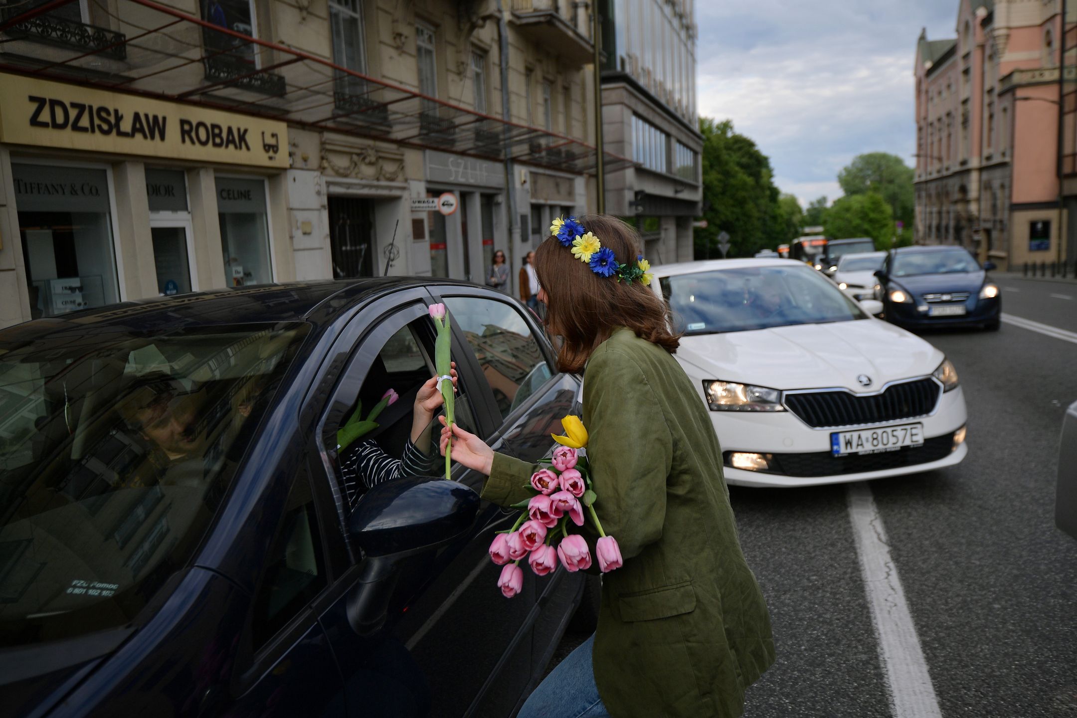 Warszawa, 29.05.2022. Obywatelka Ukrainy rozdaje kwiaty podczas Marszu Wdzięczności w Warszawie