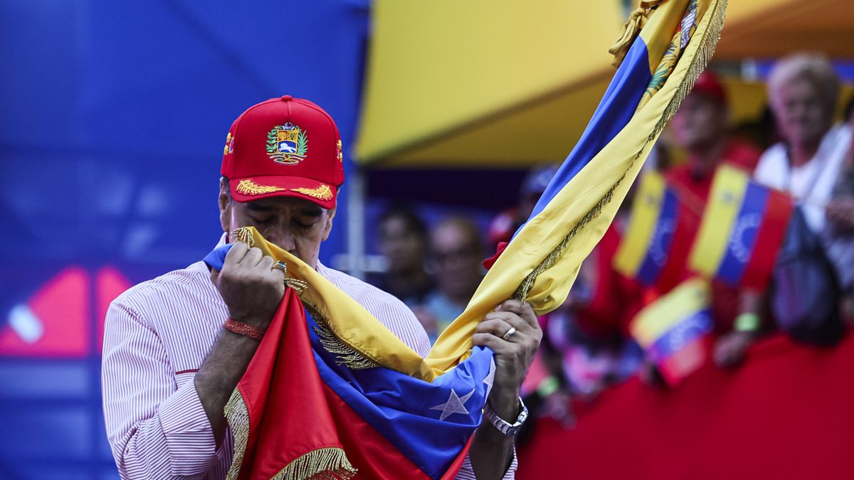 CARACAS, VENEZUELA - DECEMBER 1: President Nicolas Maduro of Venezuela kisses a Venezuelan flag during a protest to support him on December 1, 2025 in Caracas, Venezuela. Supporters gathered at Miraflores to show support and to be part of the swearing-in of the 'Integral Bolivarian Community Commands.' (Photo by Jesus Vargas/Getty Images)