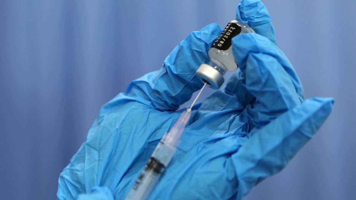 Na zdjęciu ręce w jednorazowych rękawiczkach pobierające preparat do strzykawki