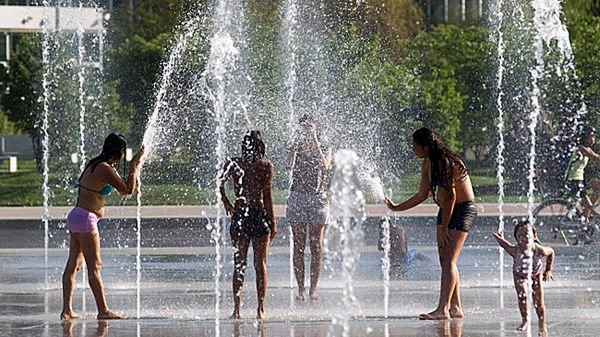 Dzieci chłodzą się w miejskiej fontannie