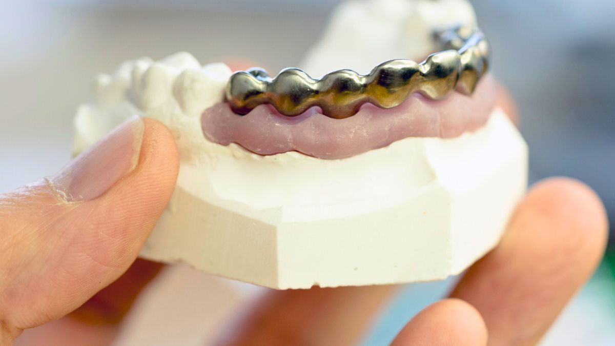 Mężczyzna trzyma w dłoniach sztuczną szczękę