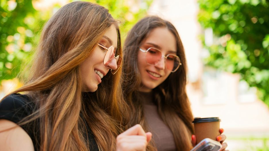 Happy two urban twin sisters are sitting in the city park and looking at the smartphone in urban area
Amazed two young twin sisters with cool sunglasses using Social media with smartphone iphone sitting on a bench in town a disposable paper coffee cup outdoors, the Concept of a communication website and social media reading email and digital chat on a smartphone,  Close-up
Mensent Photography