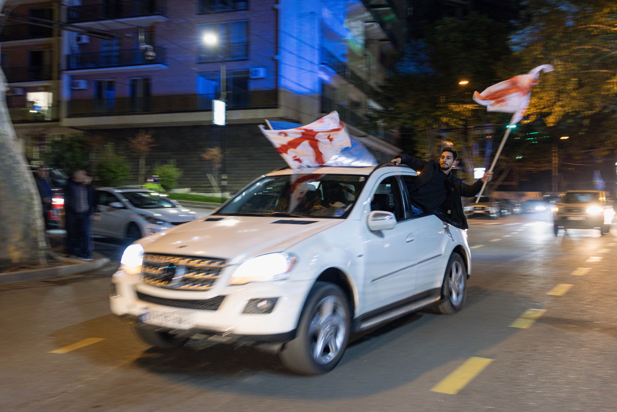 TBILISI, GEORGIA - OCTOBER 26: Georgian Dream Party supporters celebrate the exit poll results outside the new Georgian Dream headquarters during Georgian Election Day on October 26, 2024 in Tbilisi, Georgia. Georgians are voting on October 26, in a close parliamentary election that analysts say will likely determine whether or not the post-Soviet nation will take a step closer to membership in the European Union (EU). An opposition coalition is challenging the Georgian Dream ruling party, which has been in power since 2012 under the leadership of Bidzina Ivanishvili. The vast majority of Georgians are in favor of joining the EU, however the country's bid to become a member of the bloc was frozen earlier this year, following concerns over the "foreign agents" bill passed in May, which critics say represents a backslide for democracy. (Photo by Diego Fedele/Getty Images)
