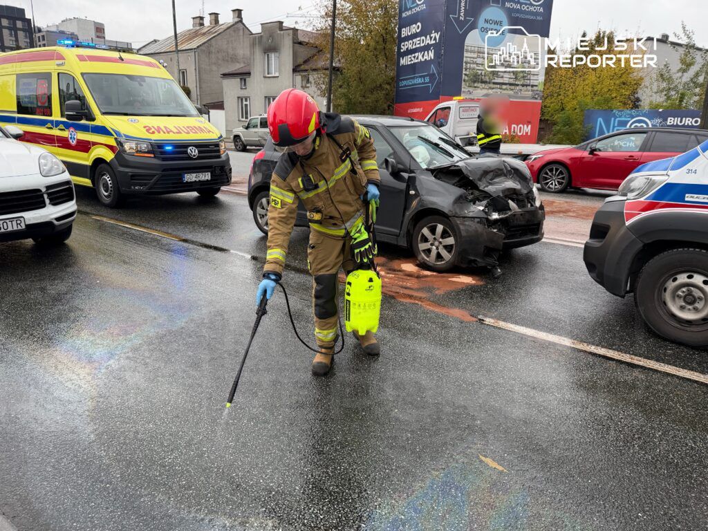 Strażak w mundurze używa urządzenia do czyszczenia drogi po wypadku samochodowym na miejskiej ulicy.