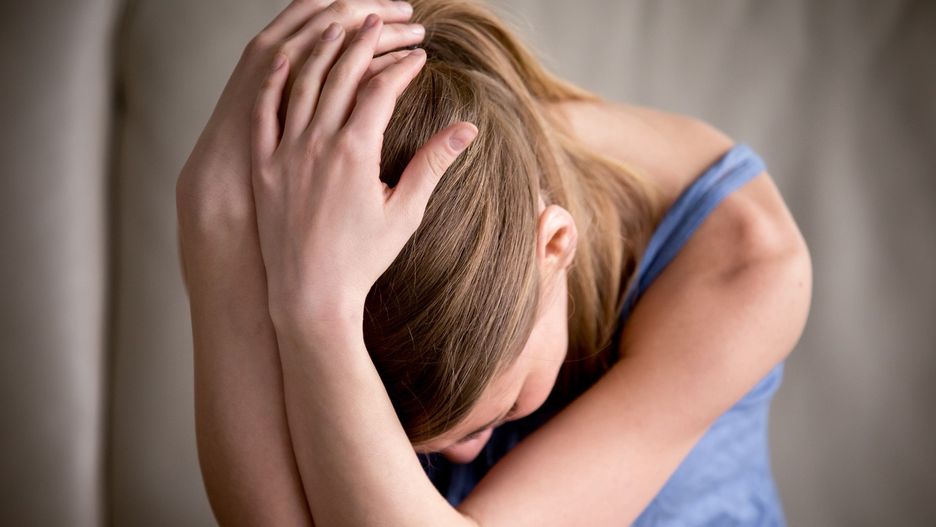 Sad teenager crying alone holding head in hands, feeling depress