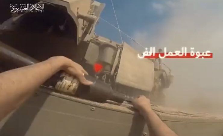Bojownik Hamasu kładzie tandemowy granat przeciwpancerny pomiędzy wieżą a kadłubem czołgu Merkawa Mk. IVM. 