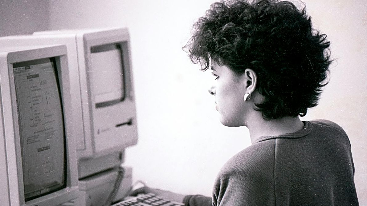 Czarno-białe zdjęcie kobiety korzystającej ze starego komputera.