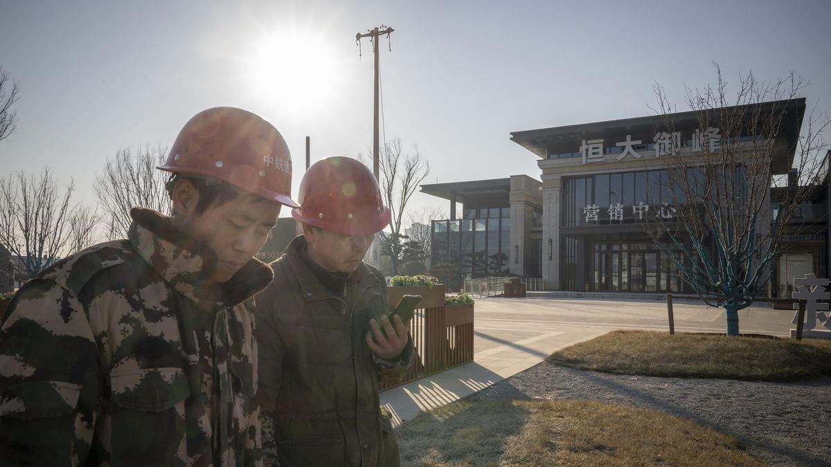 Workers walk past the sales office of a China Evergrande Group development in Beijing, China, on Thursday, Jan. 6, 2021. Evergrande is seeking to delay an option for investors to demand early repayment on one of its yuan-denominated bonds, in the latest sign of distress amid a broader real estate debt crisis. Photographer: Andrea Verdelli/Bloomberg via Getty Images