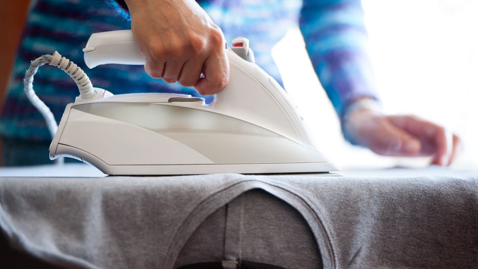 Closeup on woman's hands ironing, with selective focus