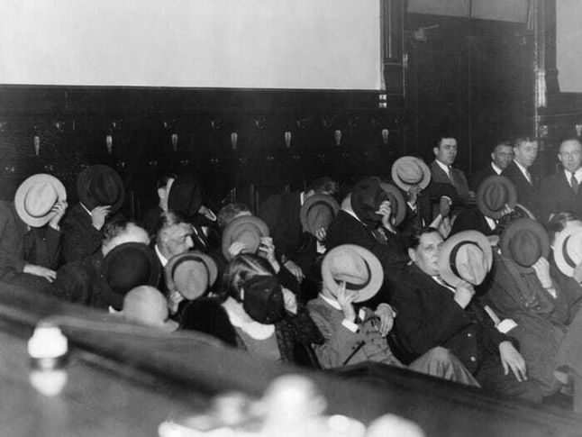 Gangsterzy ukrywający twarze podczas procesu Ala Capone (1931).