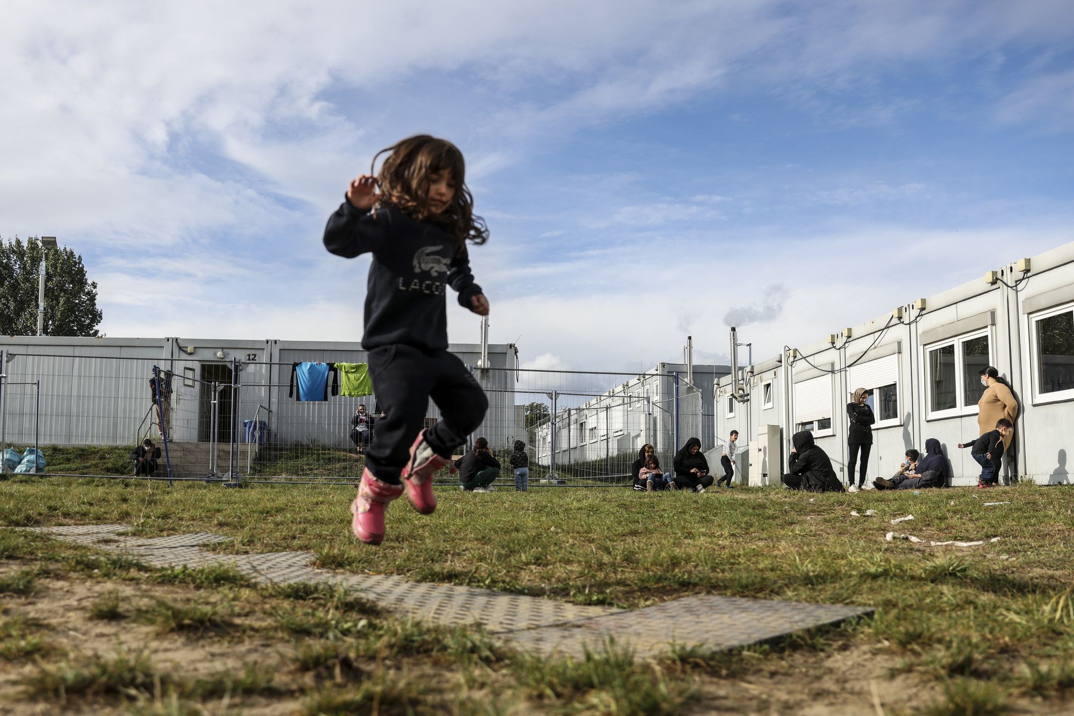 EISENHUTTENSTADT, GERMANY - OCTOBER 06: A girl plays next to a holding facility for illegal migrants on October 06, 2021 in Eisenhuttenstadt, Germany. Police have been detaining a growing number of illegal migrants, many of them from Iraq, who have been arriving at the German border from Poland, most of them most likely having arrived previously in Belarus before heading onwards. (Photo by Maja Hitij/Getty Images)