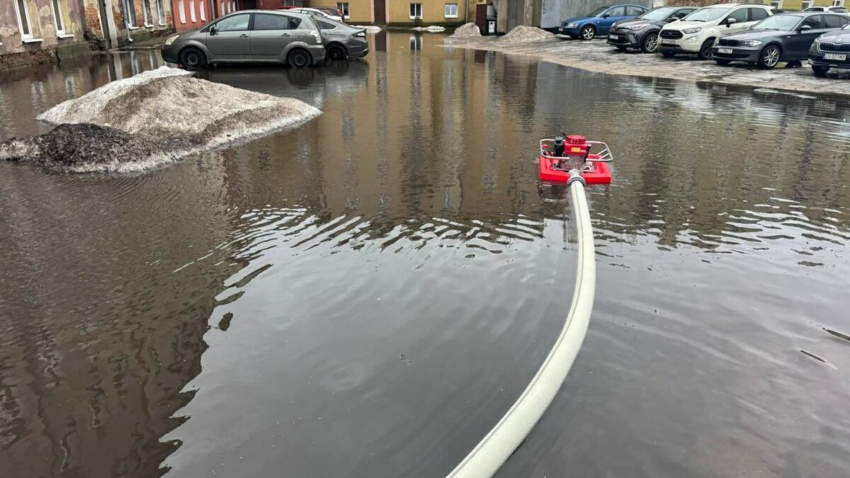 Strażacy wypompowujący wodę z zalanego podwórka kamienicy przy ul. Kunickiego