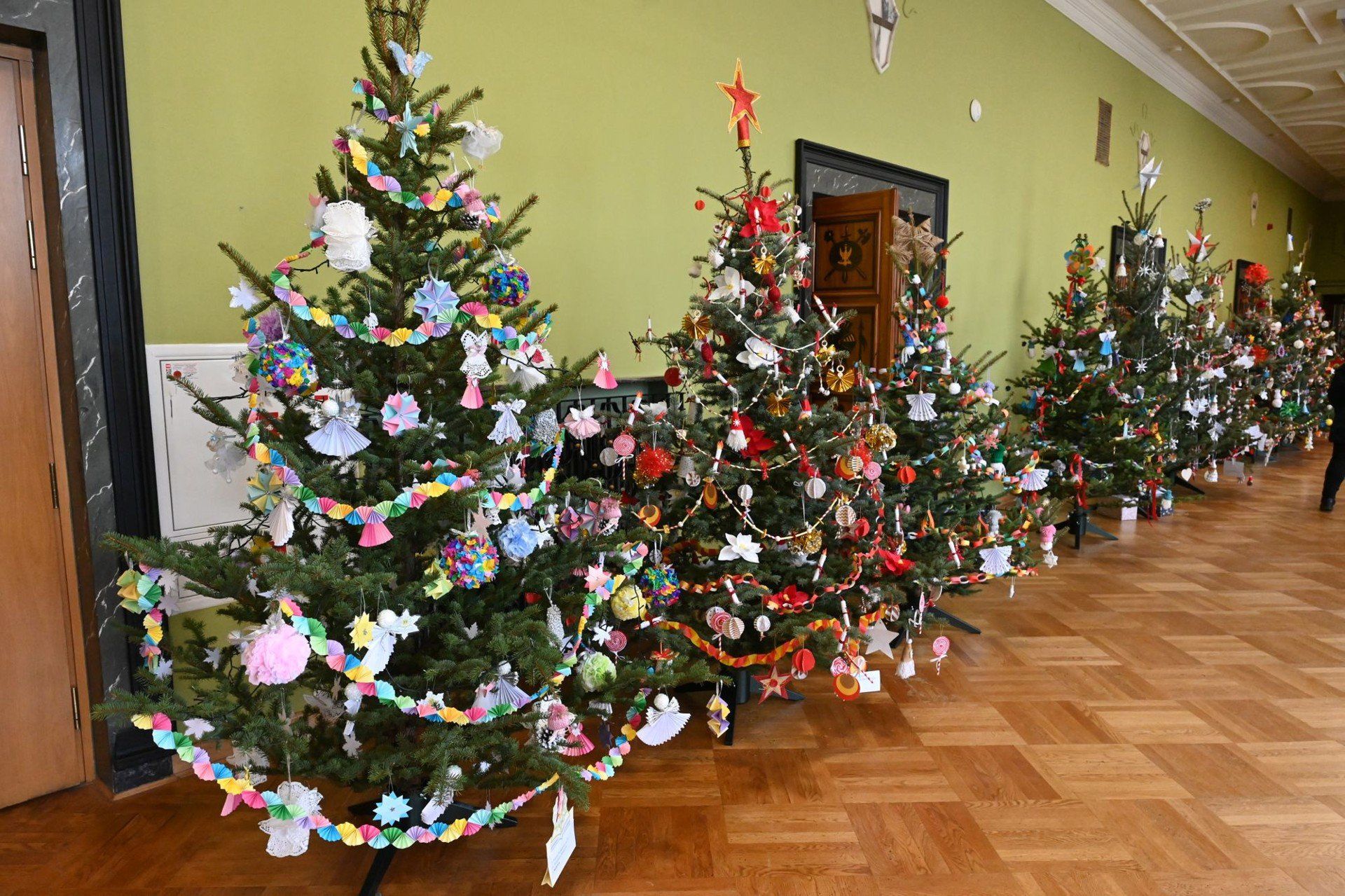 Korytarze budynku wypełnione są kolorowymi choinkami.
